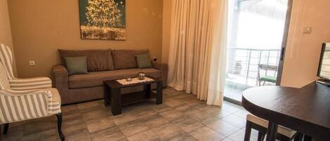 A living room with a sofa, armchair, coffee table, and a dining table.