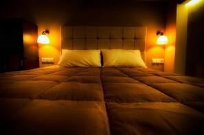 A bed with a tufted headboard, two bedside lamps, and a neutral-colored wall. - Gonis Suites - Paleochora (Kantanos-Selino)