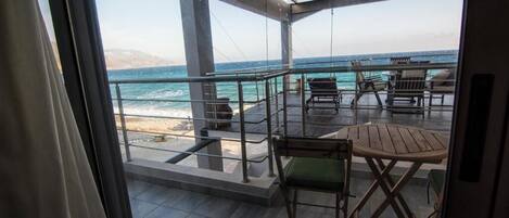 A balcony with a view of the ocean, outdoor seating, and a pergola structure.