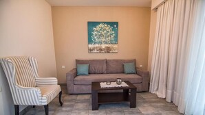 Ein Wohnzimmer mit einem gestreiften Sessel, einer Couch, einem Couchtisch und einem Baumgemälde an der Wand.