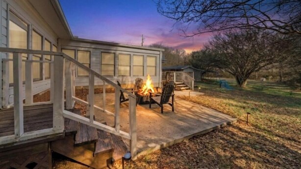 Una casa con terraza, una fogata y una escalera que lleva a la entrada.