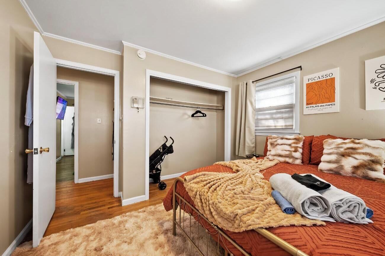Una camera da letto con un letto, un tappeto soffice, un appendiabiti e un passeggino.