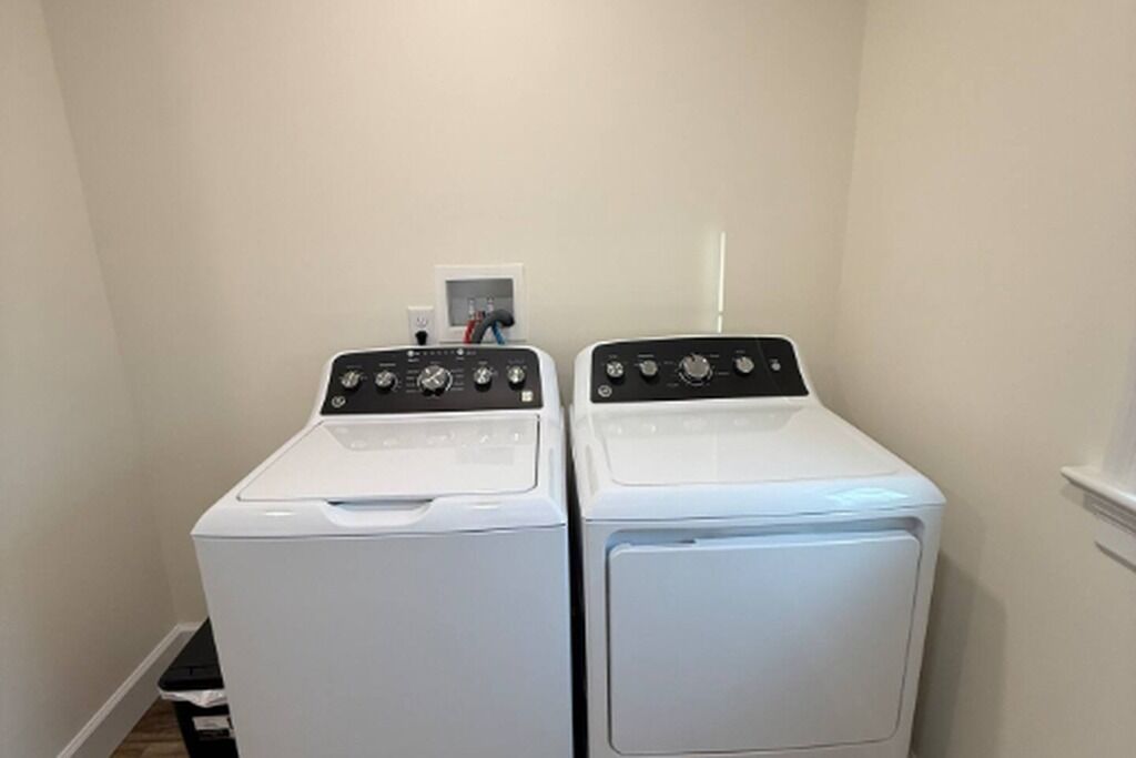 A laundry room with two white front-loading washing machines and a small shelf with a few items.