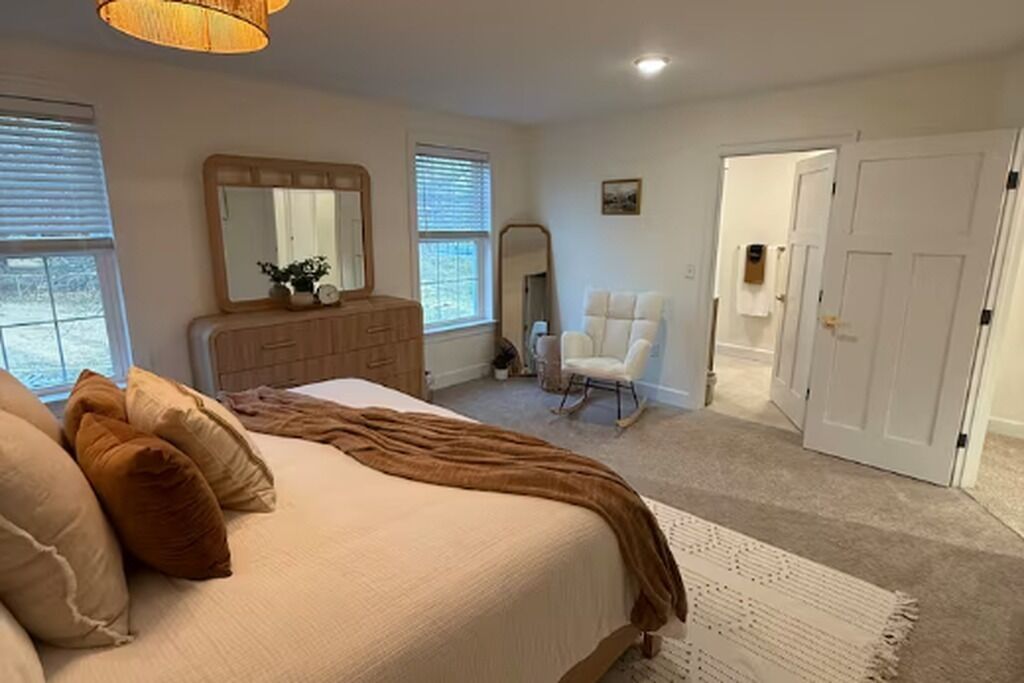 Ein Schlafzimmer mit Bett, Kommode, Stuhl und Tür.