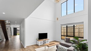 A spacious living room with a large TV, a wooden coffee table, and a grey sofa. - Spacious Central 2 story Luxury with views (San Remo)