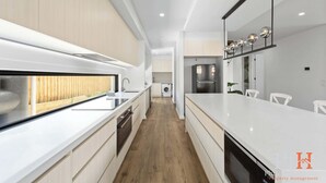 A modern kitchen with a central island, built-in appliances, and a view to a wooden deck. - Spacious Central 2 story Luxury with views (San Remo)