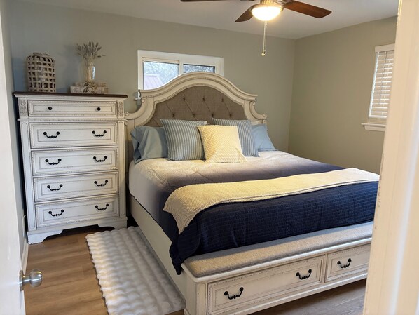 A bedroom with a bed, a dresser, a window, and a ceiling fan.