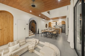 A modern interior with a wooden ceiling, a dining area, and a kitchen. - Villa Juana  (Canggu)