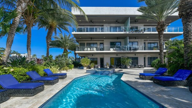 A modern hotel with a swimming pool, lounge chairs, and palm trees. - Tropical Luxury Oasis: 2 King Beds, 2.5 Baths, 3 Min Drive to Palm Beach (Noord)