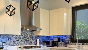 A modern kitchen with a central island, bar stools, and a large window. - Tropical Luxury Oasis: 2 King Beds, 2.5 Baths, 3 Min Drive to Palm Beach (Noord)