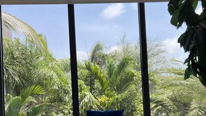 A room with a large window, a blue chair, a round table, and a wooden elephant sculpture. - Tropical Luxury Oasis: 2 King Beds, 2.5 Baths, 3 Min Drive to Palm Beach (Noord)