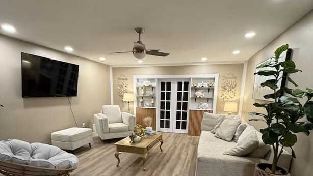 A living room with a sofa, armchair, coffee table, and a TV mounted on the wall. - Spa Beach Retreat • Sleeps 10 • 8 min to Beach (Englewood)
