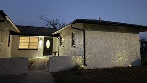 A single-story house with a dark front door, a small porch, and a pathway leading to the entrance. - Spa Beach Retreat • Sleeps 10 • 8 min to Beach (Englewood)