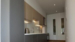 A modern kitchen with grey cabinets, a wooden floor, and recessed lighting. - Gonis Grand Luxury Suite (Kantanos-Selino)