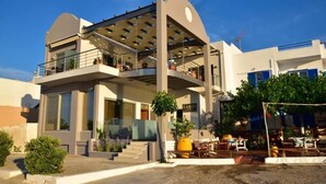 A modern two-story building with a balcony, outdoor seating area, and a sign that reads "Gonys." - Gonis Grand Luxury Suite (Kantanos-Selino)