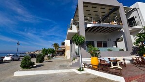 A modern building with a curved facade, outdoor seating area, and a view of the sea. - Gonis Grand Luxury Suite (Kantanos-Selino)