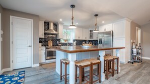 A modern kitchen with a central island, white cabinetry, and a stainless steel refrigerator. - Spacious Lakefront Getaway with Dock in Quiet Cove (Lake Ozark)