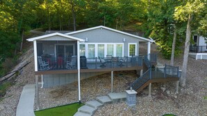 A two-story house with a covered patio and a deck. - Spacious Lakefront Getaway with Dock in Quiet Cove (Lake Ozark)