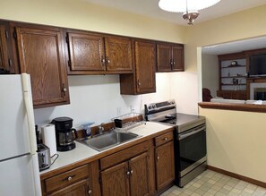 A kitchen with wooden cabinets, a refrigerator, a stove, and a coffee maker.
