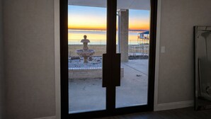 A sliding glass door leading to a balcony with a view of the beach and sunset. - Spacious 6-bedroom house on lake with extra large kitchen and great swimming. (Corsicana)