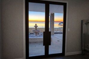 A sliding glass door leading to a balcony with a view of the beach and sunset. - Spacious 6-bedroom house on lake with extra large kitchen and great swimming. (Corsicana)