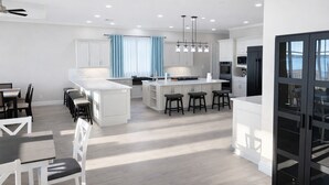 A modern kitchen with white cabinetry, a central island with stools, and a dining area with a table and chairs. - Spacious 6-bedroom house on lake with extra large kitchen and great swimming. (Corsicana)