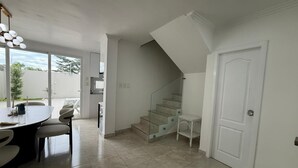 Ein geräumiger Wohnbereich mit Esstisch und Stühlen, einer Treppe und einer Tür.