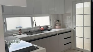 Eine moderne Küche mit weißen Schränken, einer schwarzen Arbeitsplatte, einem eingebauten Backofen und einem Fenster über der Spüle.