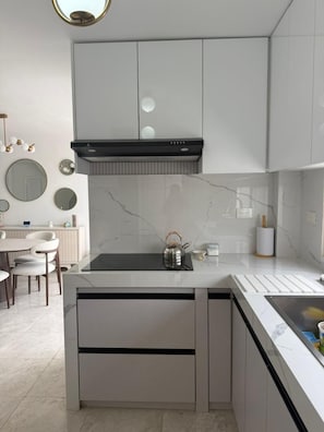 Una cocina moderna con una isla central, armarios blancos y salpicadero de mármol.