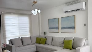 Ein modernes Wohnzimmer mit einem Ecksofa, einer Chaiselongue und einer Deckenleuchte.