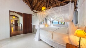 Una camera da letto con un letto a baldacchino, una lampada da comodino e vista mare.
