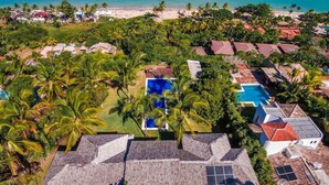 Vista aerea di un resort con diversi edifici, una piscina e una spiaggia.