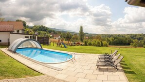 A swimming pool with a covered area, outdoor seating, and a view of a rural landscape with houses and trees. - Villa in the Stubica region with wellness, jacuzzi, sauna, and pool for relaxation (Strmec Stubički)