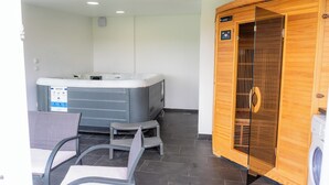 A sauna room with a wooden door, a massage table, and a small seating area with chairs. - Villa in the Stubica region with wellness, jacuzzi, sauna, and pool for relaxation (Strmec Stubički)