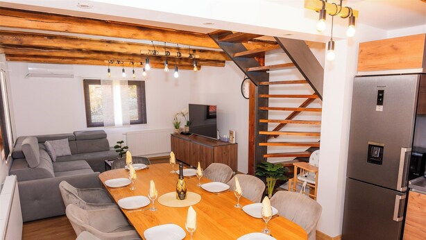 A modern kitchen with a built-in refrigerator, wooden ceiling beams, and a dining area set for six with a wooden table and six chairs. - Villa in the Stubica region with wellness, jacuzzi, sauna, and pool for relaxation (Strmec Stubički)