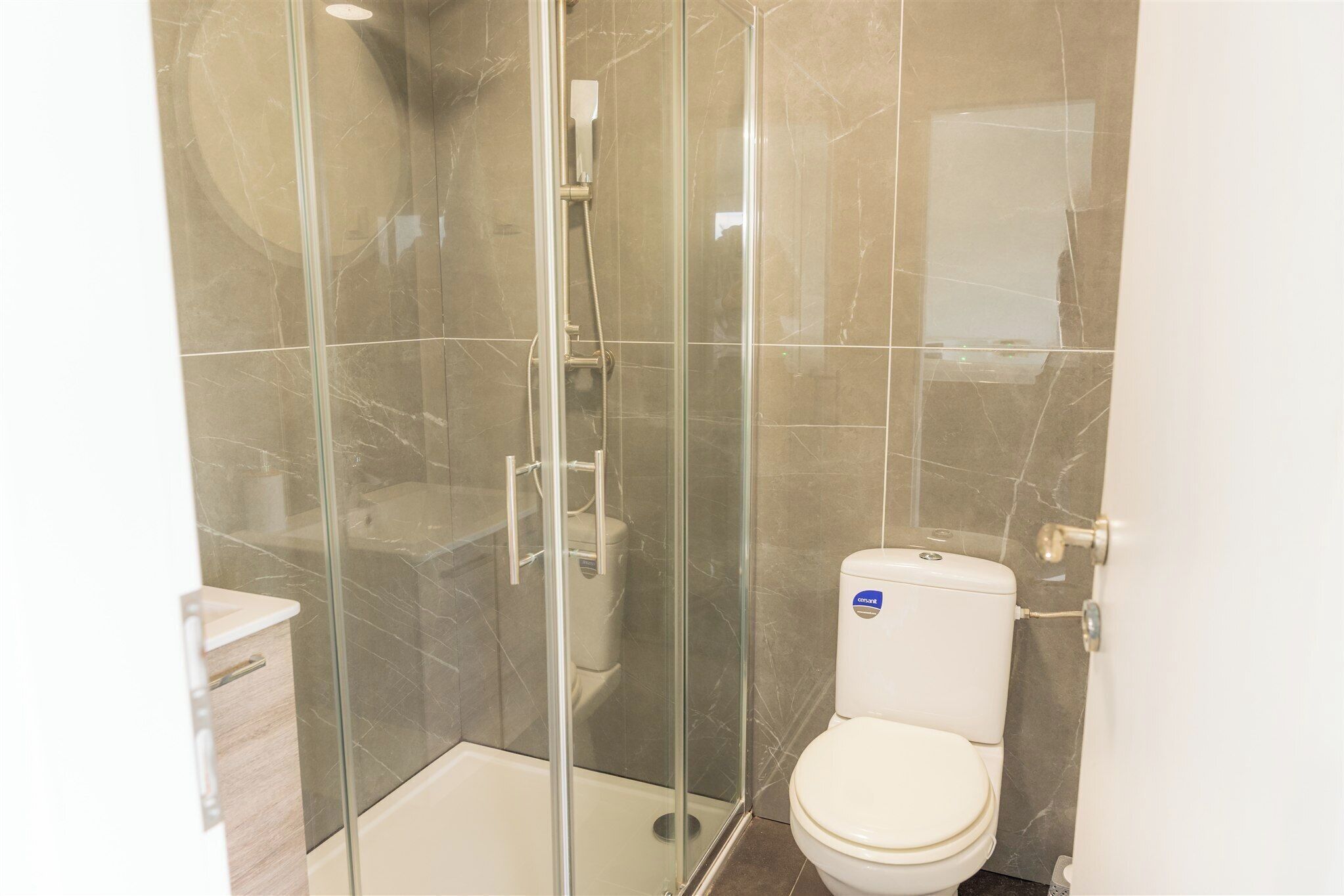 A bathroom with a glass-enclosed shower, a toilet, and a sink.