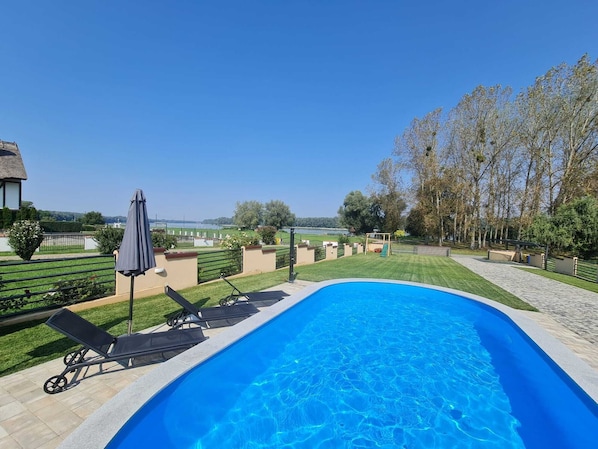 Une piscine avec des chaises longues et vue sur un lac.