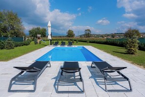 Une piscine avec trois chaises longues et un parasol.