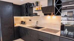 Una cocina moderna con armarios oscuros, un lavamanos doble y un horno empotrado.