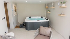 Un cuarto de spa con bañera de hidromasaje, sillones de mimbre y estantes decorativos.