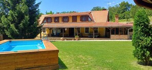 A two-story house with a swimming pool, a covered patio, and a well-maintained lawn.