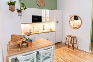 Une cuisine moderne avec des meubles blancs, un plan de travail en bois, un évier et un miroir rond.