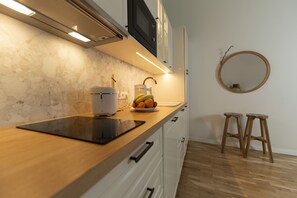 Une cuisine moderne avec un plan de travail en bois, une machine à café, un panier de fruits et un miroir rond accroché au mur.