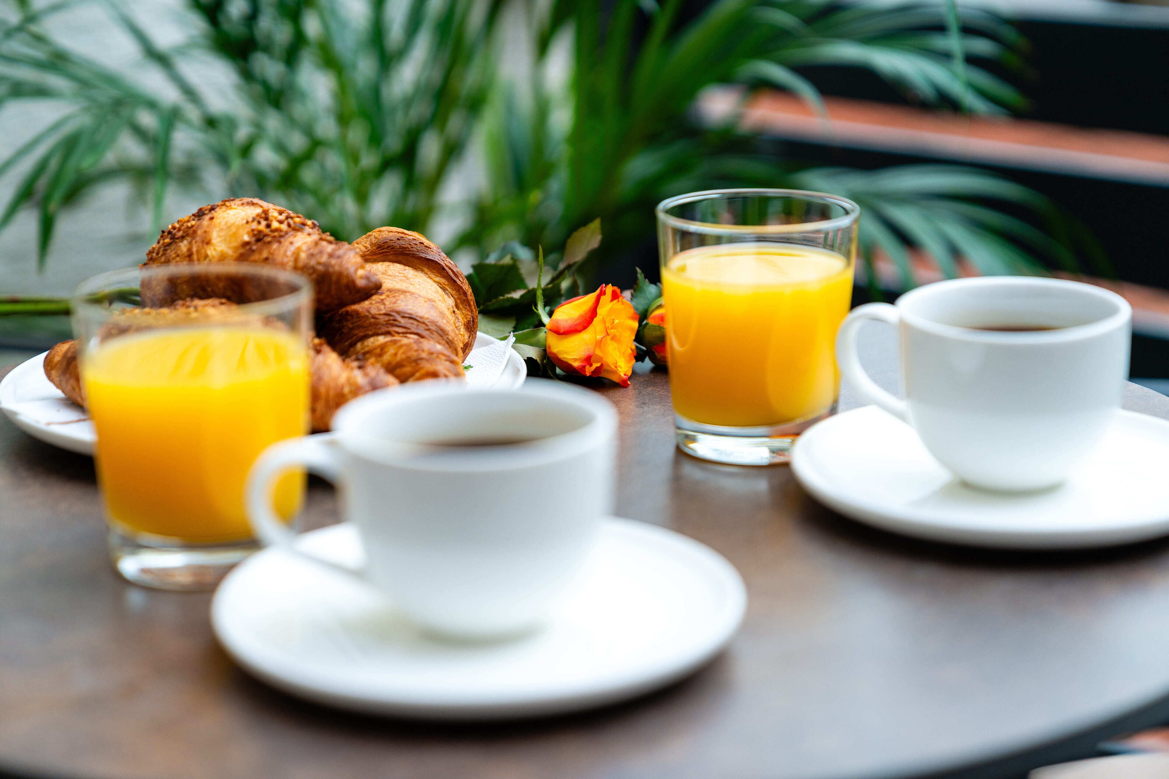 A breakfast setting with croissants, orange juice, and coffee on a table.