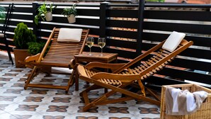 Une terrasse avec deux fauteuils de jardin en bois, une petite table et un panier en osier.