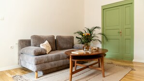 Un salon avec un canapé gris, une table basse en bois et une porte verte.