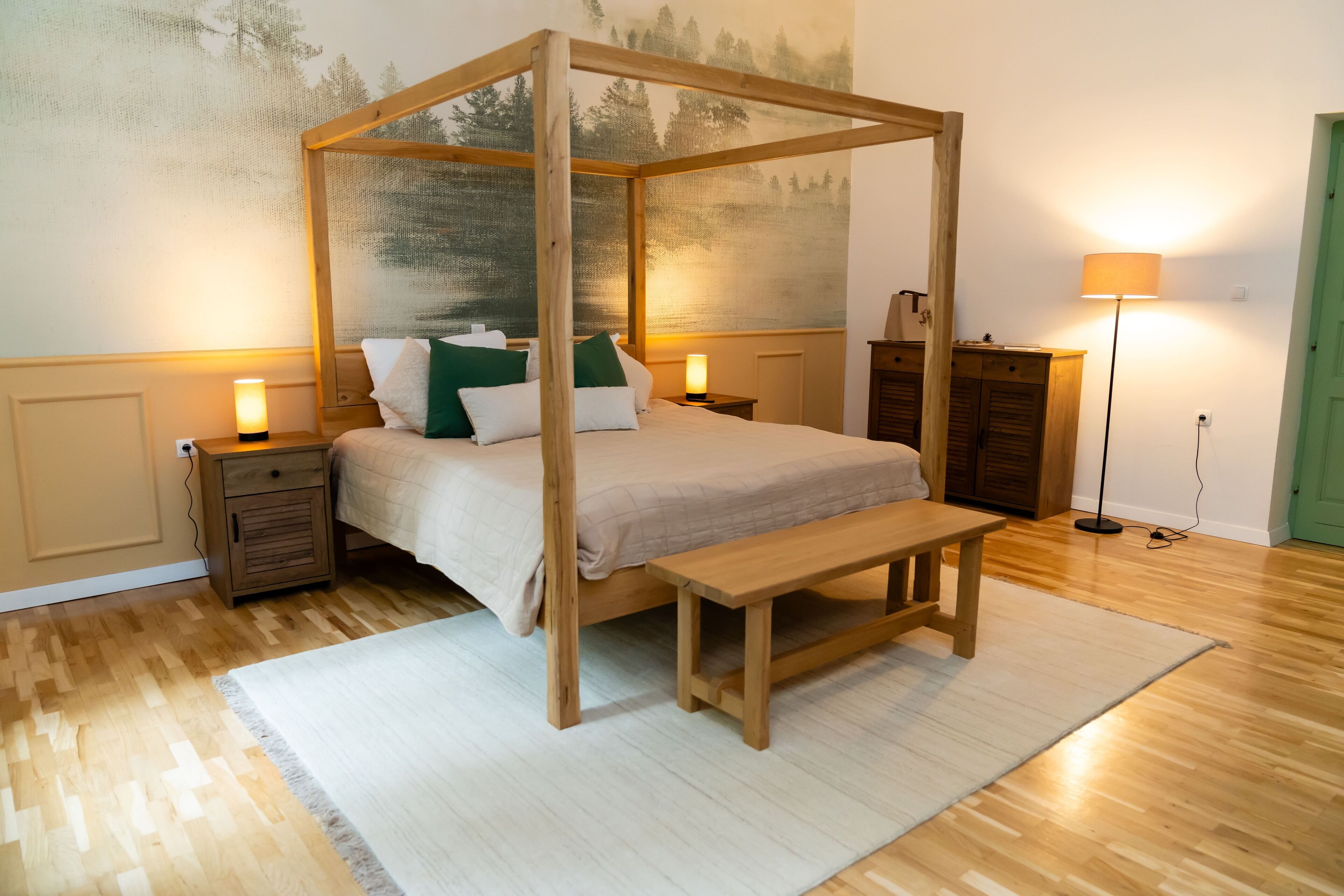 A four-poster bed with a wooden frame, a bench, and a nightstand with a lamp.