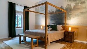 Une chambre à coucher avec un lit à baldaquin, une table de chevet avec une lampe, un banc et une grande fenêtre avec des rideaux.