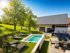 Une maison moderne dotée d’une piscine, de mobilier d’extérieur et d’un jardin bien entretenu.