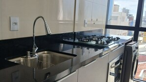 Una cocina moderna con un lavamanos de acero inoxidable, una estufa a gas y un horno empotrado.